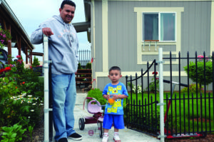 Father and son stand in front of a house